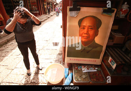 A Chinese woman washes her hair in an alley of small souvenir shops, one featuring a poster of late helmsman Mao Zedong, in Lijiang, northern Yunnan Province, on September 29, 2012.   During the Cultural Revolution under the Red Guard, Mao's already glorified image manifested into a personality cult that influenced every aspect of Chinese life, and still persists to across the country.    UPI/Stephen Shaver Stock Photo