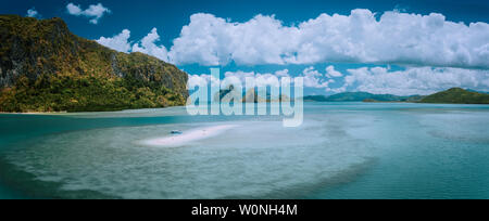 Palawan, Philippines. Aerial panoramic scenic picture of sandbar with lonely tourist boat in turquoise coastal water and cloudscape. El Nido Bacuit Stock Photo