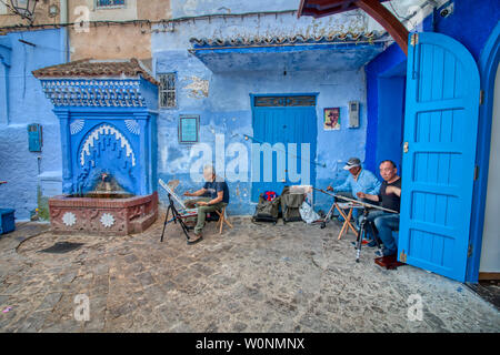 Chefchaouen, Morocco - May 03, 2019: Asian tourists painting pictures on a beautiful street in the tourist city of Chefchaouen, in northern Morocco Stock Photo