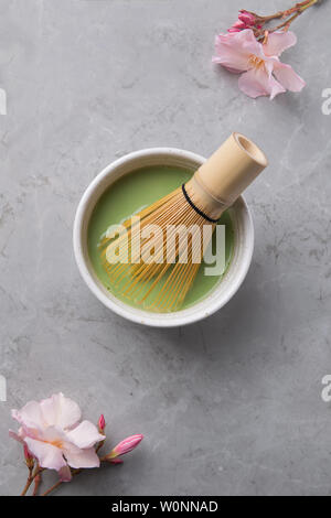 Top view of green tea matcha in a bowl on grey marble surface with beautiful oleander flower Stock Photo