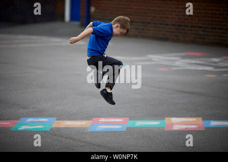 Posed by model,  small child in school uniform playing traditional playground games Stock Photo