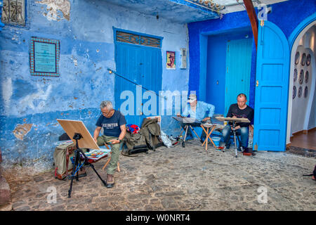 Chefchaouen, Morocco - May 03, 2019: Asian tourists painting pictures on a beautiful street in the tourist city of Chefchaouen, in northern Morocco Stock Photo