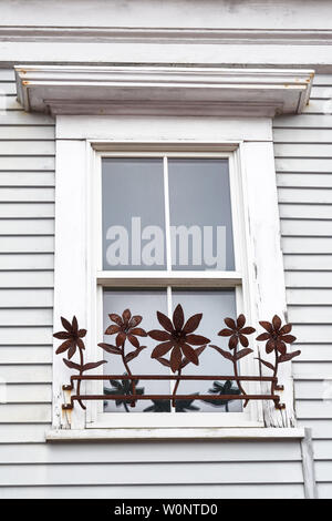 rusty metal flower decor on the white painted window of a house Stock Photo