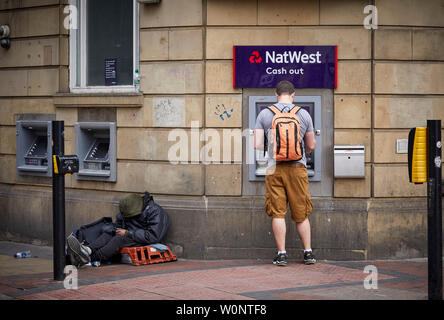 Manchester city centre, Natwest cash machine ATM with person begging next to the whole in the wall dispenser Stock Photo