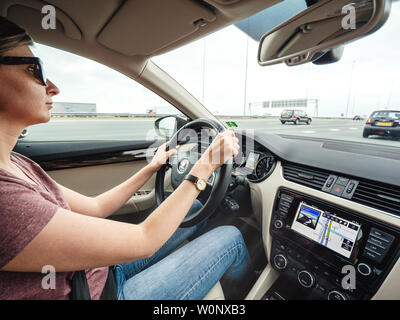 Haarlem, Netherlands - Aug 15, 2018: Woman driving luxury car on Dutch six lane highway with GPS instruction on the dashboard