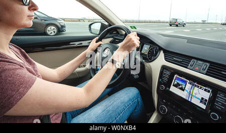 Haarlem, Netherlands - Aug 15, 2018: Wide image of caucasian woman driving luxury car on Dutch six lane highway with GPS instruction on the dashboard