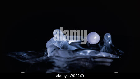 Splash of milk droplets in close up macro high resolution isolated against a black background Stock Photo