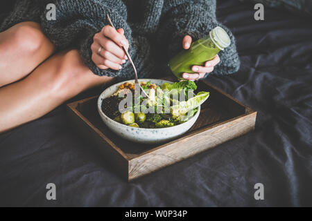 Healthy vegan bowl on tray and woman eating Stock Photo