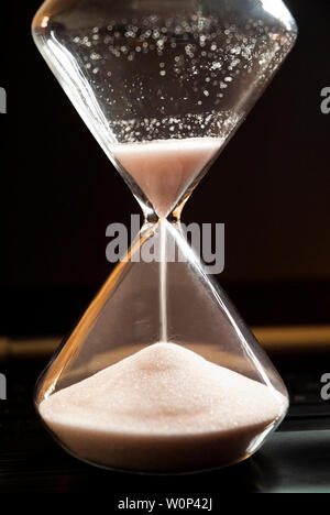 An hourglass sits on a laptop computer. Stock Photo