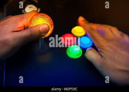 Lighted arcade bubble top joystick and buttons being played by retro gamer. Stock Photo