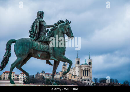 Equestrian statue of Louis XIV on Place Bellecour with Basilica Notre Dame de Fourvière in background Stock Photo