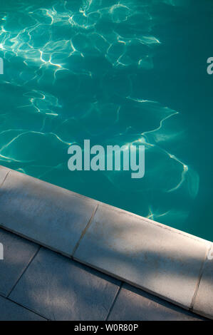 The Edge Of A Swimming Pool With Shadows And Reflections Playing On The Waters Surface Stock Photo