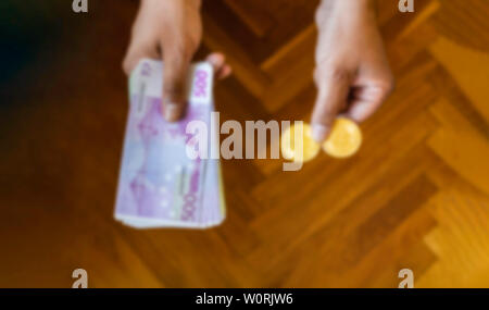 Blurred image of euro 500 bills and gold coins in hand background - Blur hands offering choice between cash money and gold bitcoins cryptocurrency - C Stock Photo