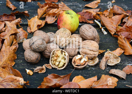 Walnuts, autumn leaves and wild apples on old, grunge oak table, side view Stock Photo