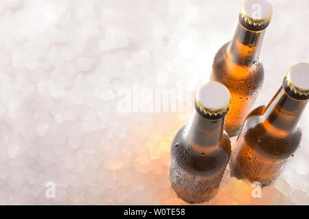 Three bottles of closed beers on crushed ice. Horizontal composition. Top view. Stock Photo