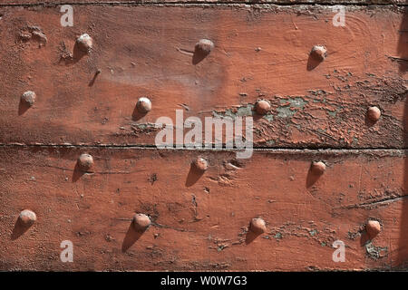 Old wooden, chipped door with nails texture background in sunlight Stock Photo