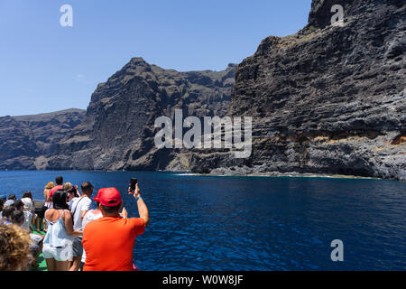 TENERIFE, CANARY ISLANDS, SPAIN - JULY 26, 2018: Tourists take pictures of the vertical cliffs Acantilados de Los Gigantes (Cliffs of the Giants). Stock Photo