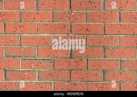 Red brick wall pattern with unevenly distributed small rock chips in brick material. Stock Photo