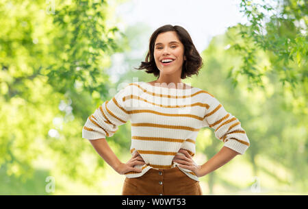smiling woman in pullover with hands on hips