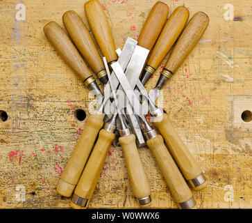 Group of assorted woodworking chisels isolated on wooden bench grunge surface. Stock Photo