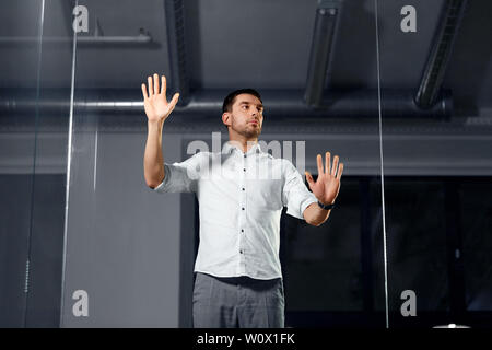 businessman touching glass wall at night office Stock Photo