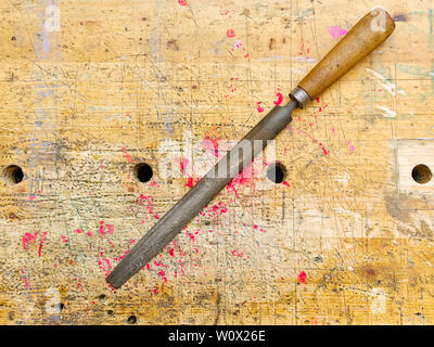Rasp tool  isolated on aged wooden bench grunge surface with splash of red paint. Stock Photo