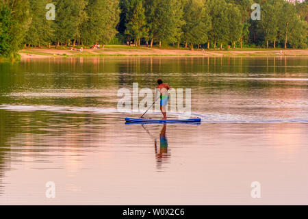 Image of stand up paddleboarding man on a lake during sunset Stock Photo