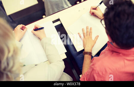 students writing to notebooks at exam or lecture Stock Photo