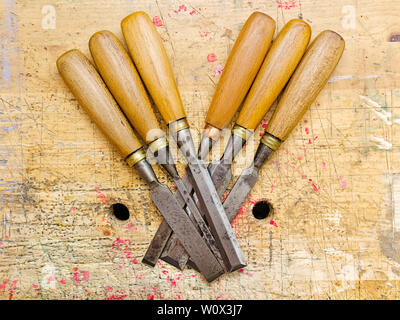 Group of assorted woodworking chisels isolated on wooden bench grunge surface. Stock Photo