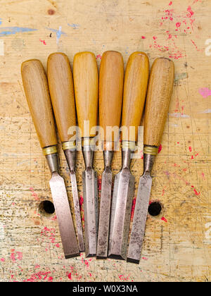 Group of assorted woodworking chisels isolated on wooden bench grunge surface. Stock Photo