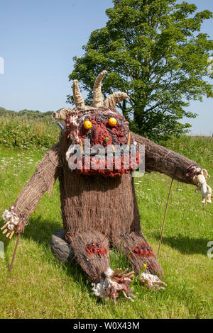 Halsall, Lancashire. 28th June 2019. UK Weather.  Sunny summer sculptures appear over night. Grotesque, quirky, straw filled scarecrows, film characters, caricatures with scary masked faces, line the streets & fields of the rural village of Halsall. Credit: MWI/AlamyLiveNews Stock Photo