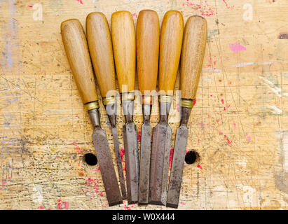 Group of assorted woodworking chisels isolated on wooden bench grunge surface. Stock Photo