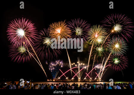 cheering crowd watching colorful fireworks and celebrating on the beach during festival Stock Photo