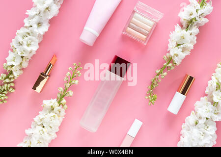 facial cosmetic beauty products with white flower on pastel pink desktop background. natural beauty skin care layout, top view, flat lay.