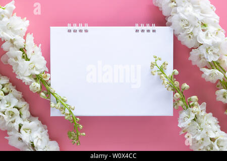 flat lay of blank paper desk spiral calendar decorate with white flower isolated on pink background Stock Photo