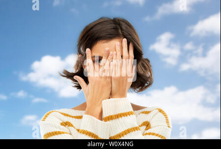 young woman looking by one eye through her fingers Stock Photo