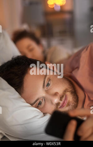 man using smartphone while girlfriend is sleeping Stock Photo