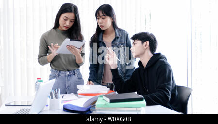 Group Students Smile and have fun and using tablet It also helps to share ideas in the work and project. And also review the book before the exam Stock Photo
