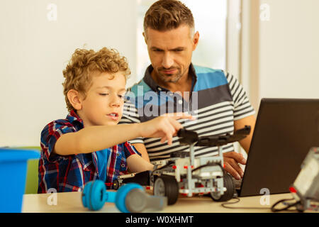 What is this. Nice smart boy pointing with his hand while asking a question to his teacher Stock Photo