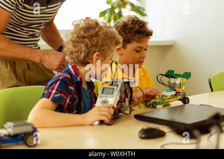 Technical club. Nice smart boys looking at the car models while working together on the project Stock Photo