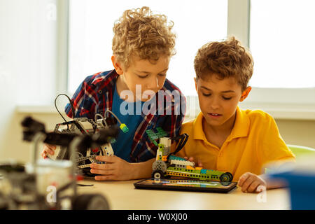 How to construct. Nice serious boy looking at the scheme while constructing a car according to it Stock Photo