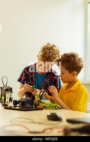 Careful process. Nice intelligent boys looking at the car details while constructing it together Stock Photo