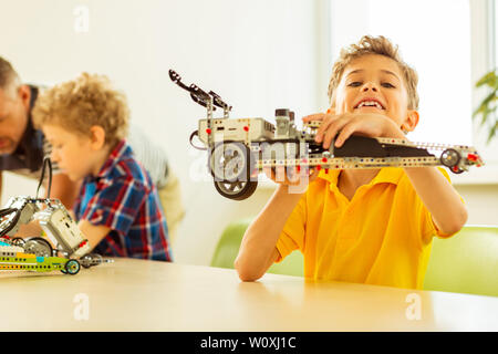 Look what I made. Joyful nice boy smiling to you while being proud of his work Stock Photo