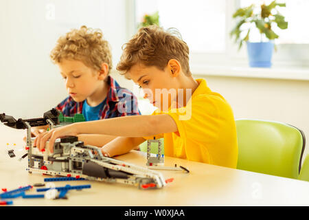 Diligent pupils. Nice serious boys being focused on their work while preparing an engineering project Stock Photo