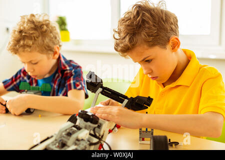 Broken toy model. Smart cute boy trying to understand the problem while fixing a toy car Stock Photo