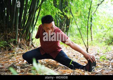 (190628) -- CHONGQING, June 28, 2019 (Xinhua) -- Liu Yi takes exercise in a bamboo forest in Nanchuan District, southwest China's Chongqing, June 27, 2019. Despite losing his right arm in an accident at the age of nine, 44-year-old Liu Yi has never lowered his head towards destiny. After graduation from a vocational school in 1994, he tried a good many jobs like dishwasher, fruit dealer and coal miner. Since 2010, he has decided to start up his own business at his hometown by organizing villagers to plant bamboo roots and raising chickens. His efforts paid off. In 2016, however, Liu Yi got int Stock Photo