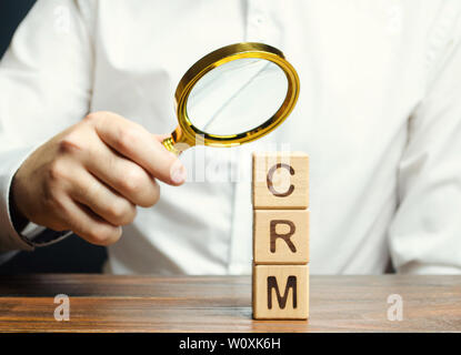 Wooden blocks with the word CRM (Customer Relationship Management) and businessman. Automation strategies for interacting with clients. Increase sales Stock Photo