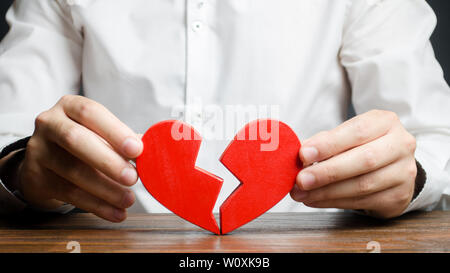 A man collects a broken heart in his hands. Concept of love and relationships. Family psychotherapist services. Reconciliation. Saving the family. Sea Stock Photo