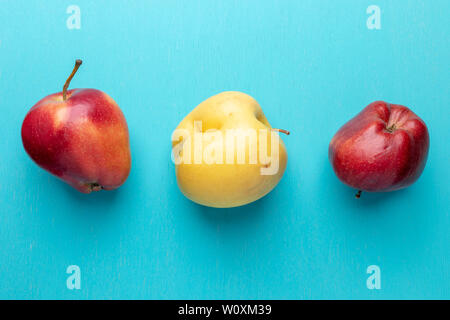 Three ugly red and yellow apples are lying in row on turquoise painted wooden  background. Waste zero concept. Top view,  flat lay, copy space. Stock Photo