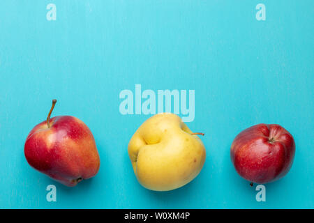 Three ugly red and yellow apples are lying in line in bottom on turquoise painted wooden  background. Waste zero concept. Top view,  flat lay, copy sp Stock Photo